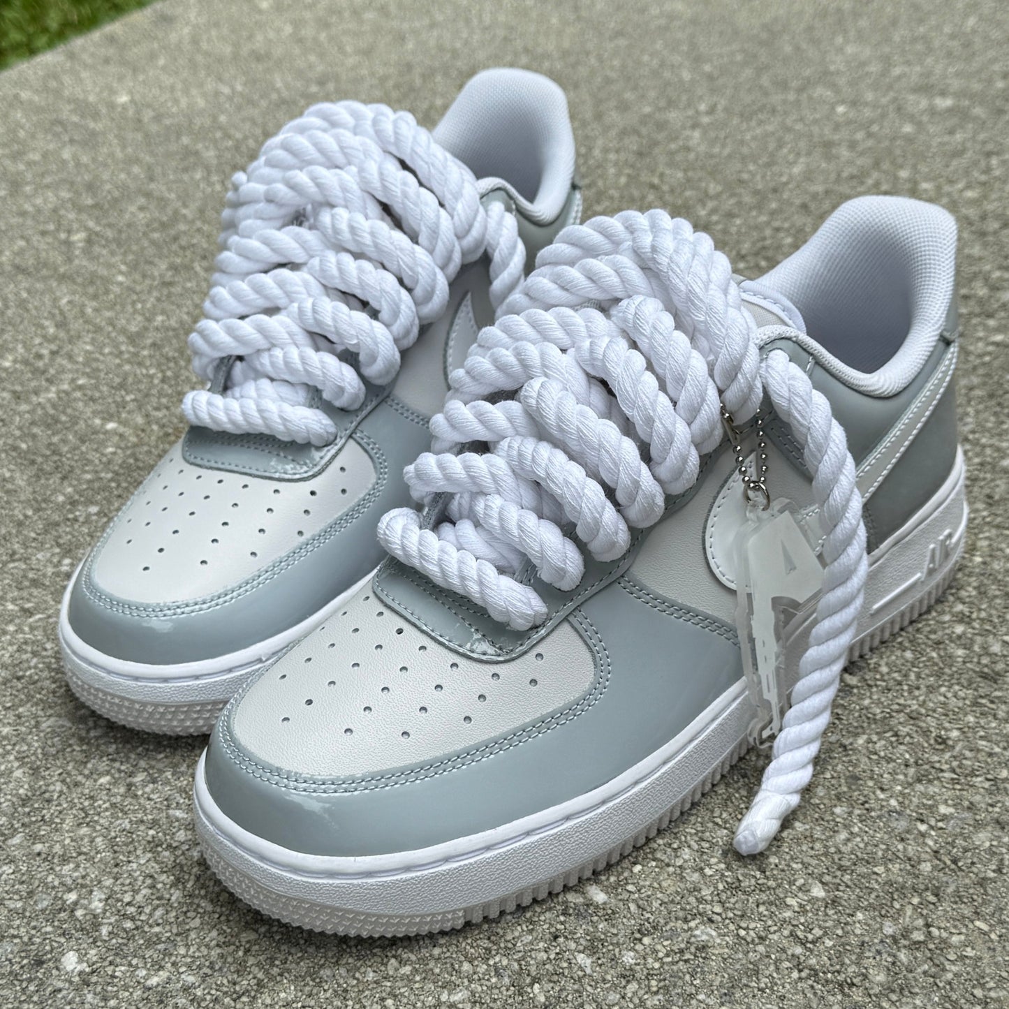 Gray sneakers with white rope laces on a concrete surface